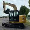 Side profile of a certified CAT 308E2 used compact excavator for sale at the yard.